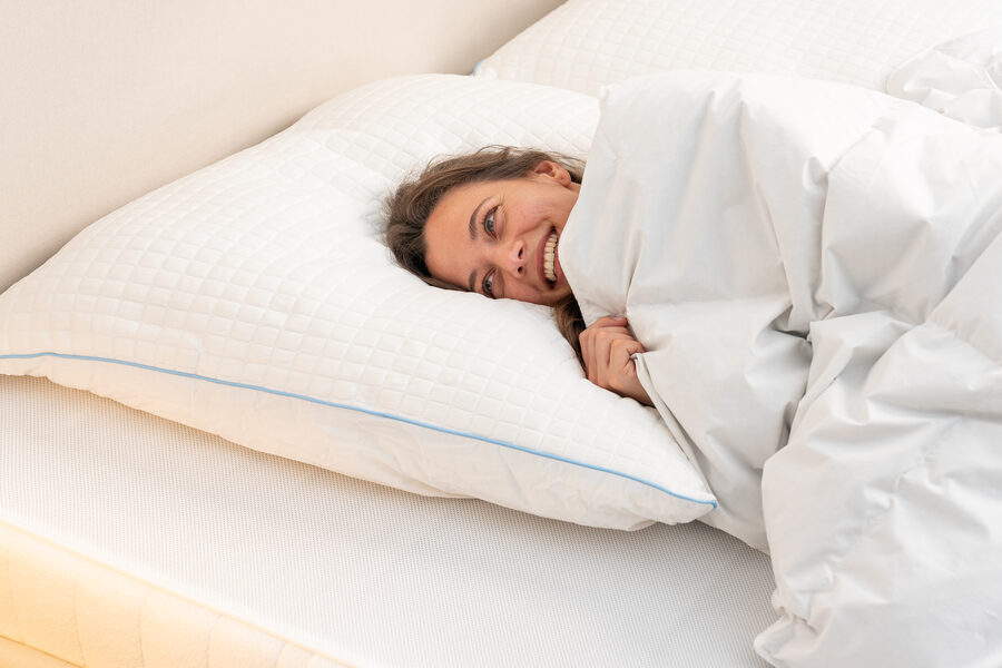 Frau wacht ausgeruht und gut gelaunt in ihrem Bett auf